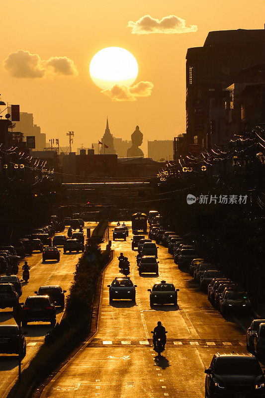 橙色的日落天空在佛祖(青铜雕像)，和Wat Paknam Bhasicharoen(皇家寺庙)，从立交桥上看高速公路上的交通堵塞，摩托车，汽车，空气污染，烟雾，汽车烟雾